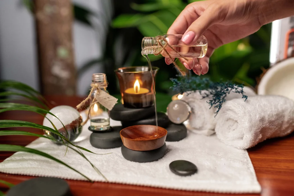 hand-pours-oil-from-jar-aromatic-oils-standing-stones-stone-therapy-located-terry-towel
