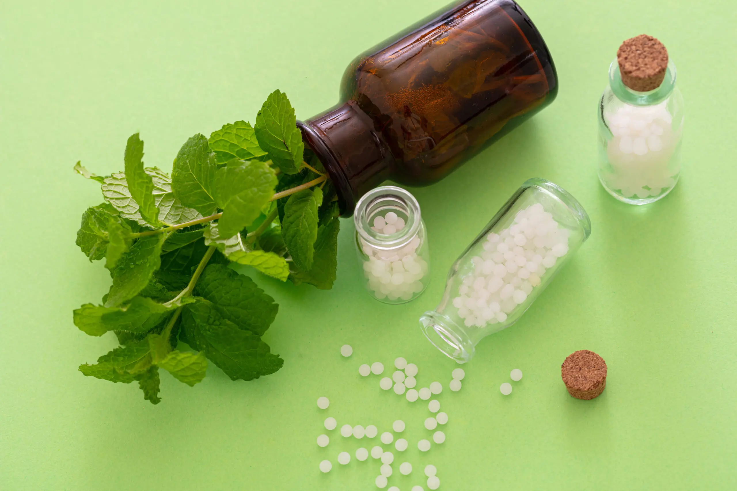 Homeopathy, globules scattered out of glass bottle, green background